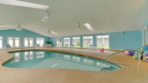 An indoor swimming pool with clear windows, a tiled floor, and a few lounge chairs. - Studio condo with furnished patio, sauna, & pool - near beaches (Wells)