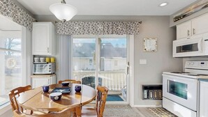 A kitchen with a dining table, chairs, a microwave, and a stove. - Studio condo with furnished patio, sauna, & pool - near beaches (Wells)