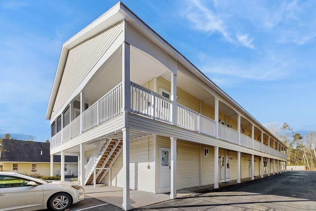 A two-story motel with a central staircase, balconies, and a parking lot.
