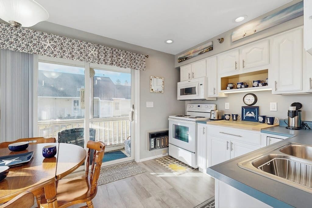 A modern kitchen with white cabinets, a microwave, a stove, and a sink.