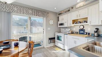 A modern kitchen with white cabinets, a microwave, a stove, and a sink.