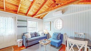 Una habitación acogedora con techo de madera, un sofá azul, una mesita pequeña y una mesa de comedor con sillas.