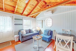 Une pièce chaleureuse avec un plafond en bois, un canapé bleu, une petite table et une table à manger avec des chaises.