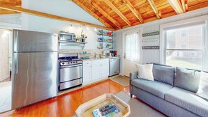 Una cocina funcional con electrodomésticos modernos, un sofá gris y techo de madera.