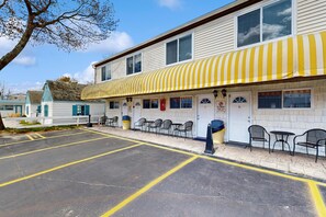 Ein Motel mit gelb gestreiftem Vordach, einem Parkplatz und Außenbereich mit Sitzgelegenheiten.