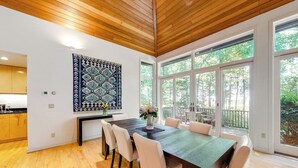 Un comedor con techo de madera, ventanas amplias y un tapiz con diseño.