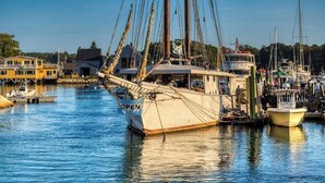 Ein Hafen mit einem großen Segelschiff, umgeben von kleineren Booten und Gebäuden.