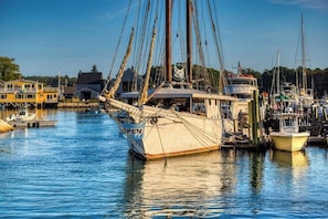 Ein Hafen mit einem großen Segelschiff, umgeben von kleineren Booten und Gebäuden.