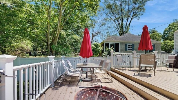 Eine Terrasse mit Gartenmöbeln, einer Feuerstelle und roten Sonnenschirmen.