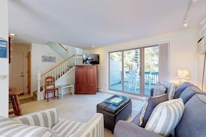 A living room with a sofa, a coffee table, a television, and a staircase leading to another room. - Cape Cod style condo with grill, pool, sauna, & gym - near beach (Old Orchard Beach)