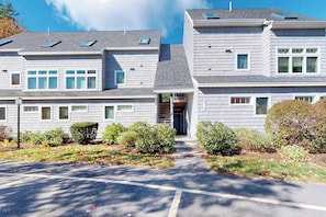 A two-story building with a central entrance, multiple windows, and a parking lot. - Cape Cod style condo with grill, pool, sauna, & gym - near beach (Old Orchard Beach)