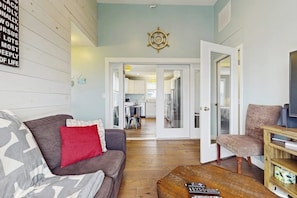 A living room with a sofa, a red pillow, a wooden coffee table, and a television. - Charming condo with outdoor pool, private washer/dryer, partial estuary view (Wells)