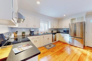 A modern kitchen with white cabinets, stainless steel appliances, and a wooden floor. - Idyllic Retreat near the Beach with Fast WiFi, Two Living Areas & Full Kitchen (Kennebunk)