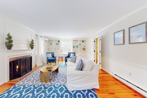 A living room with a fireplace, a white sofa, blue chairs, and a patterned rug. - Idyllic Retreat near the Beach with Fast WiFi, Two Living Areas & Full Kitchen (Kennebunk)