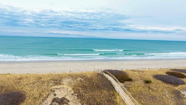 A beach with a sandy shore, a wooden boardwalk, and the ocean in the background. - Lovely townhome near golf with gas grill, patio, high-speed WiFi, & full kitchen (Ogunquit)