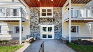 A building with a stone facade, a 'LOOKOUT' sign, and a covered entrance with benches. - Ocean-view condo overlooking Ogunquit Beach with balcony, pool & tennis (Ogunquit)