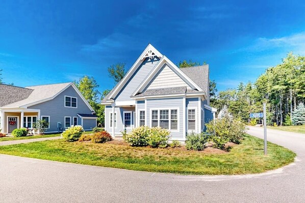 A two-story house with a gabled roof, a front porch, and a well-maintained lawn. - Bright and comfortable 2-level home near the beach w/shared pool, WiFi (Arundel)