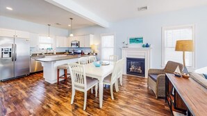 Une cuisine moderne avec des meubles blancs, un îlot central et un coin repas avec des chaises blanches.