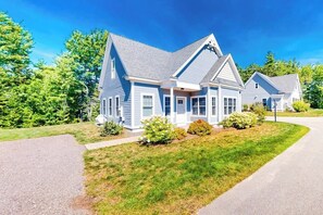 A two-story house with a gabled roof, a front porch, and a driveway. - Bright and comfortable 2-level home near the beach w/shared pool, WiFi (Arundel)
