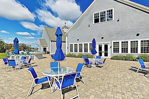 A building with a large patio area featuring outdoor seating and umbrellas. - Bright and comfortable 2-level home near the beach w/shared pool, WiFi (Arundel)