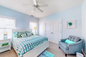 A bedroom with a bed, a chair, a door, and a ceiling fan. - Bright and comfortable 2-level home near the beach w/shared pool, WiFi (Arundel)