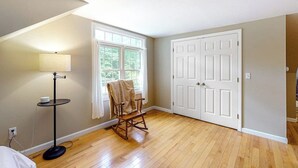 A room with a wooden floor, a rocking chair, a lamp, a door, and a window. - Riverfront, upstairs studio with fast WiFi & fireplace - dog-friendly (Ogunquit)