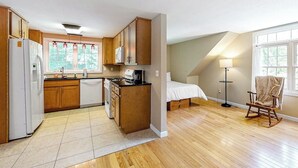 A compact kitchen with wooden cabinets, a refrigerator, and a stove. - Riverfront, upstairs studio with fast WiFi & fireplace - dog-friendly (Ogunquit)