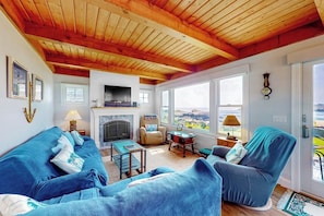 Ein gemütliches Wohnzimmer mit Kamin, blauer Möbel und großen Fenstern mit Aussicht.