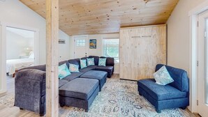 A modern interior with a wooden ceiling, a large sectional sofa, a small sofa, and a patterned rug. - Shorelands, Unit 44-3  | Condo in Kennebunk with pool and playground access (Kennebunk)