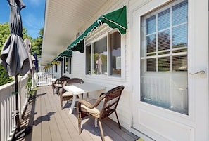 A covered deck with outdoor furniture, a white railing, and a green awning.
