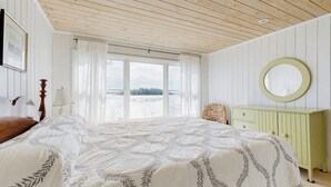 Ein Schlafzimmer mit einem Bett, einem Schminktisch, einem Spiegel und einem Fenster mit Aussicht.