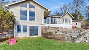 Ein zweigeschossiges Haus mit Balkon, einer Steinschmalseite und einem Rasenstück.