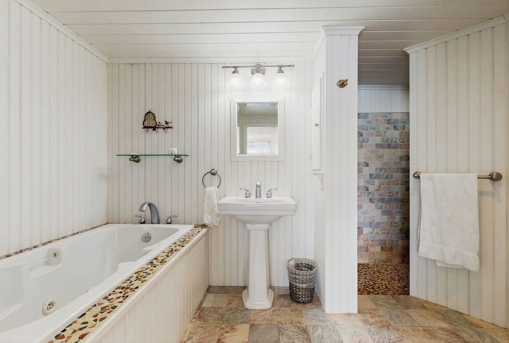 A bathroom with a bathtub, a pedestal sink, and a mirror.