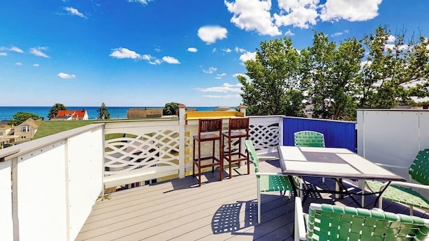 Una terrazza con mobili da esterno, un recinto bianco a grigliato e vista sul mare.