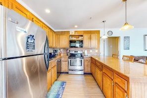 A modern kitchen with wooden cabinets, stainless steel appliances, and a central island. - Ocean-view condo with gorgeous sunrises, deck, & WiFi - walk to beach & pier (Old Orchard Beach)