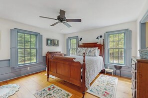 A bedroom with a wooden bed, two windows, a ceiling fan, and a small bedside table. - Spacious retreat with peaceful seclusion, Wifi, Patio & BBQ Grill (Freeport)