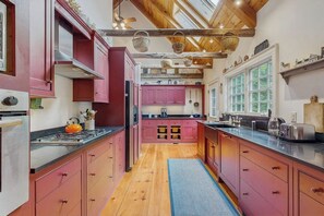 A kitchen with wooden beams, pink cabinets, and a blue rug. - Spacious retreat with peaceful seclusion, Wifi, Patio & BBQ Grill (Freeport)