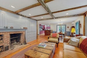 A spacious living room with a fireplace, wooden beams, and a sofa. - Spacious retreat with peaceful seclusion, Wifi, Patio & BBQ Grill (Freeport)