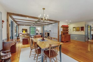 A spacious dining area with a wooden table and chairs, a chandelier, and a kitchen in the background. - Spacious retreat with peaceful seclusion, Wifi, Patio & BBQ Grill (Freeport)