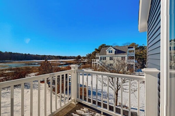 A residential area with a house, a wooden deck, and a view of a river.