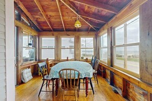 A dining area with a wooden ceiling, large windows, and a table with chairs. - Charming oceanfront cottage w/enclosed porches, steps to the water Dogs OK (Wells)