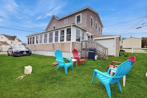 A two-story house with a garage, a lawn with outdoor furniture, and a car parked in the driveway. - Charming oceanfront cottage w/enclosed porches, steps to the water Dogs OK (Wells)