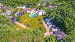 An aerial view of a residential area with houses, a swimming pool, and a road. - Charming condo with pool and deck space (Wells)