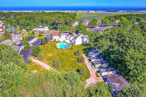 An aerial view of a residential area with houses, a swimming pool, and a road.