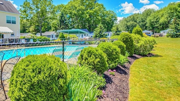 A residential area with a swimming pool, surrounded by well-maintained lawns and trees. - Charming condo with pool and deck space (Wells)