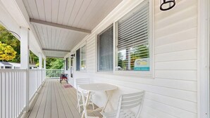 A covered porch with white railings and a small table and chairs. - Charming condo with pool and deck space (Wells)