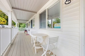 A covered porch with white railings and a small table and chairs.
