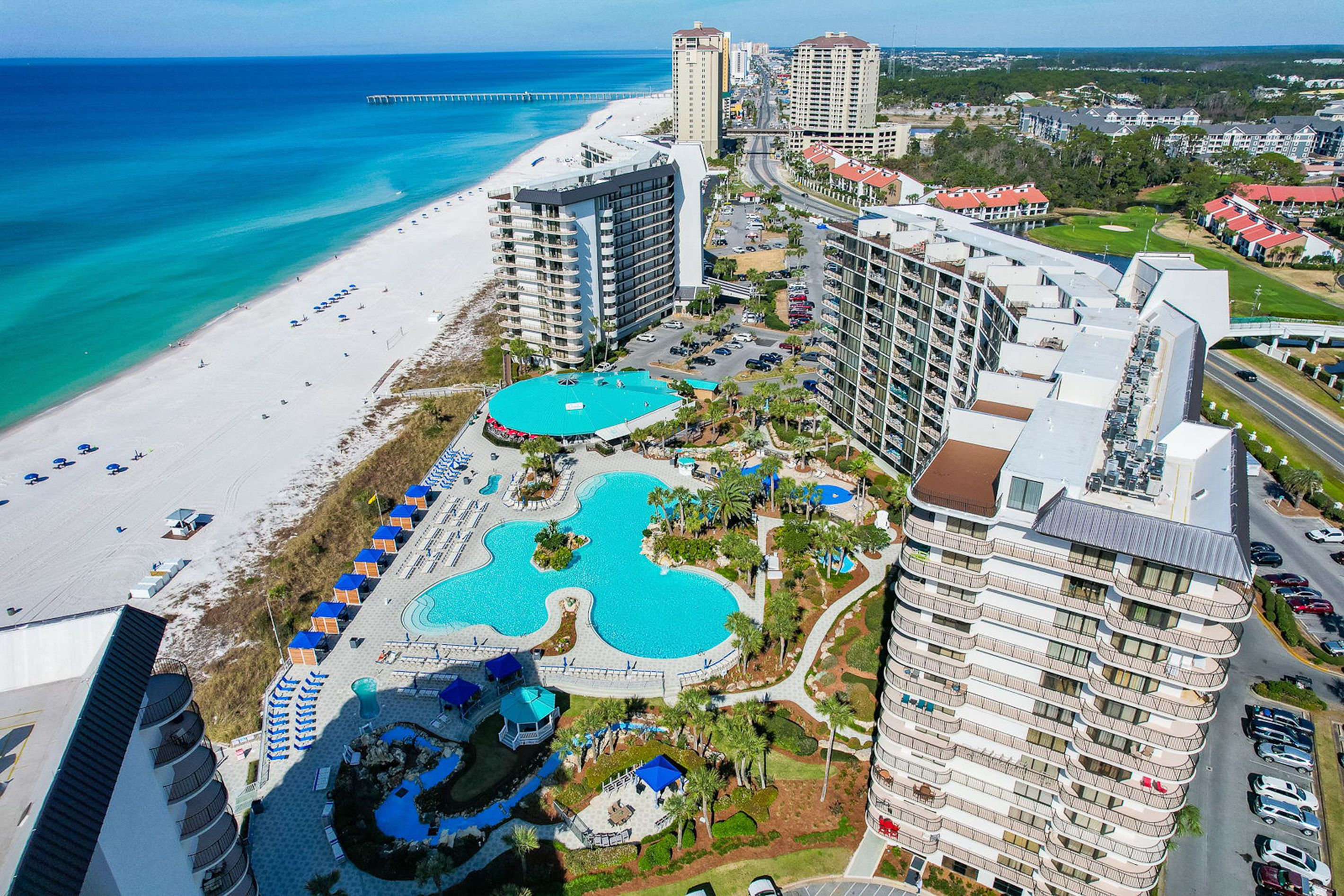 A resort with a beach, a large pool complex, and high-rise buildings.