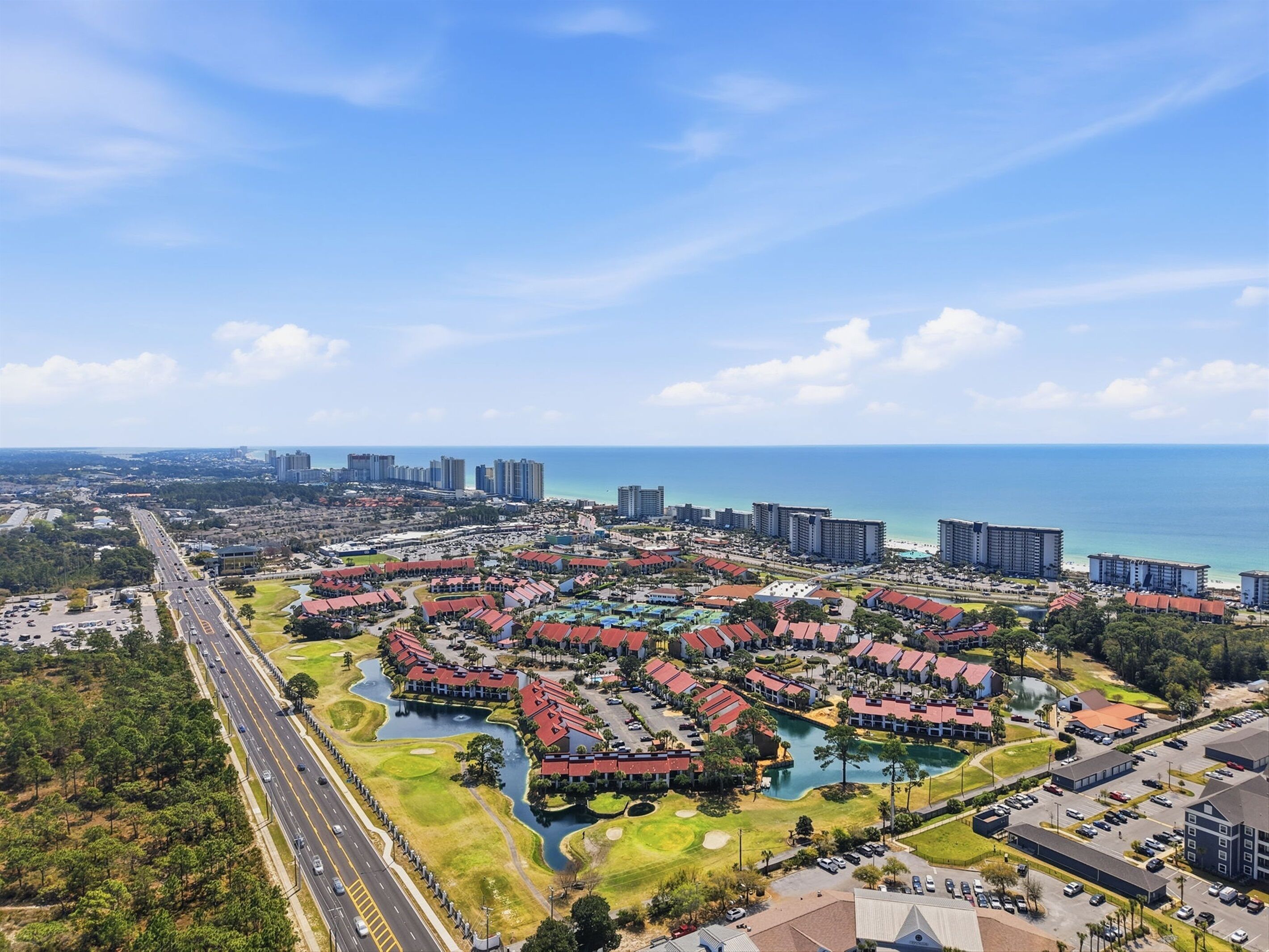 A resort with multiple buildings, a golf course, and a large body of water.