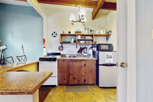 Una cocina compacta con un mueble de madera, un microondas, una estufa y un lavaplatos.